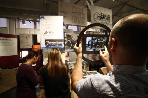 An augmented reality tablet in a car steering wheel shaped frame being used in the Lanchester Interactive Archive space at Coventry University library, 2017. 